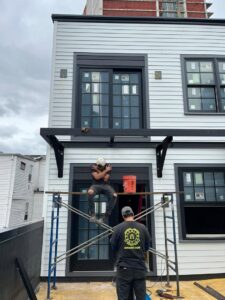 Workers installing an exterior metal awning or balcony structure on a building by Advanced Welding All in One Fabrication LLC in Guttenberg, NJ.