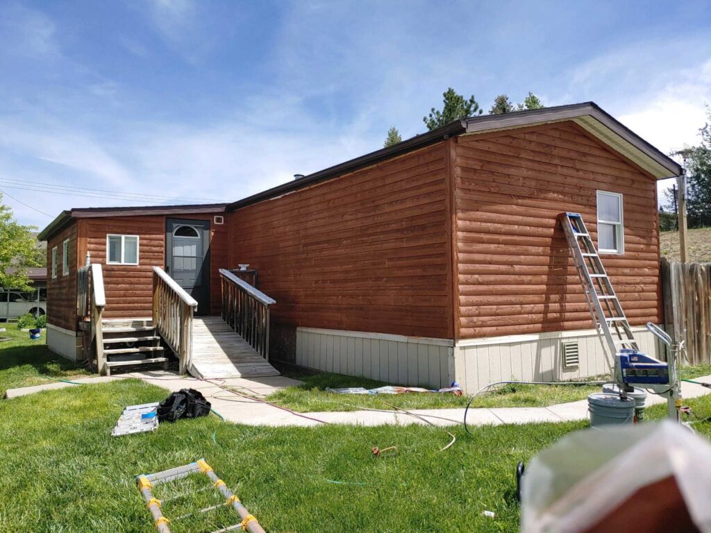 Exterior view of a mobile home with new siding or stain, showing ongoing renovation work by Rapid Renovations LLC in Rapid City, SD.