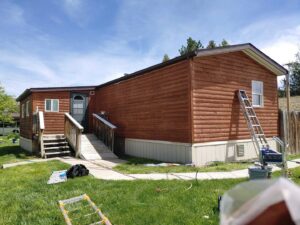 Exterior view of a mobile home with new siding or stain, showing ongoing renovation work by Rapid Renovations LLC in Rapid City, SD.