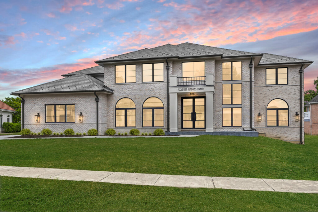 The exterior of a modern custom home with large windows and a grand entrance at dusk by DJK Custom Homes in Naperville, IL