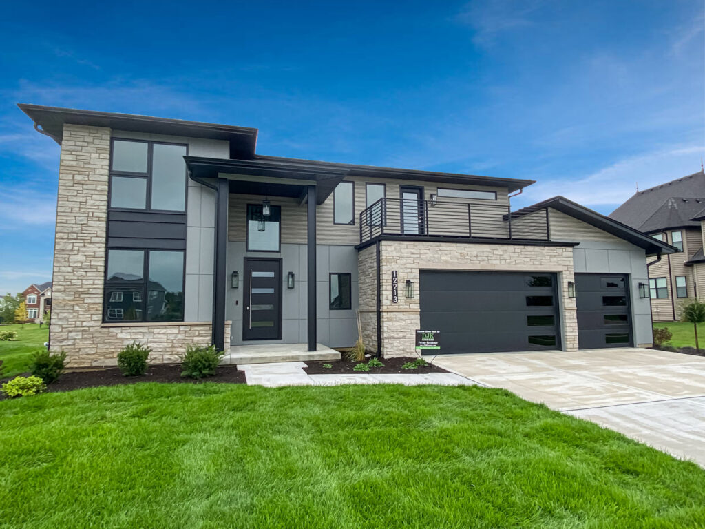 The exterior of a modern custom home with stone accents, dark siding, and a two-car garage by DJK Custom Homes in Naperville, IL