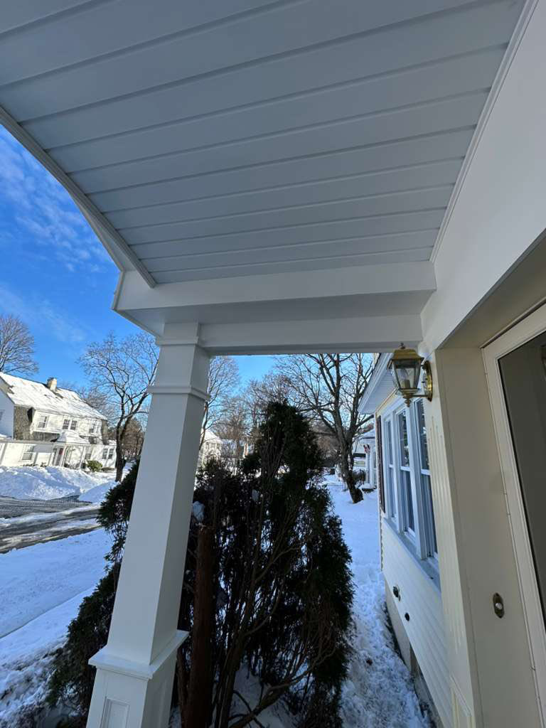 An exterior view of a newly installed porch ceiling with a light fixture and white columns, completed by Remodel or Renew Home Improvement in Worcester, MA.