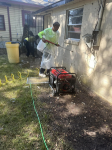 A handyman performing exterior pressure washing on a house wall for Snell & Sons Construction LLC in Mobile, AL.