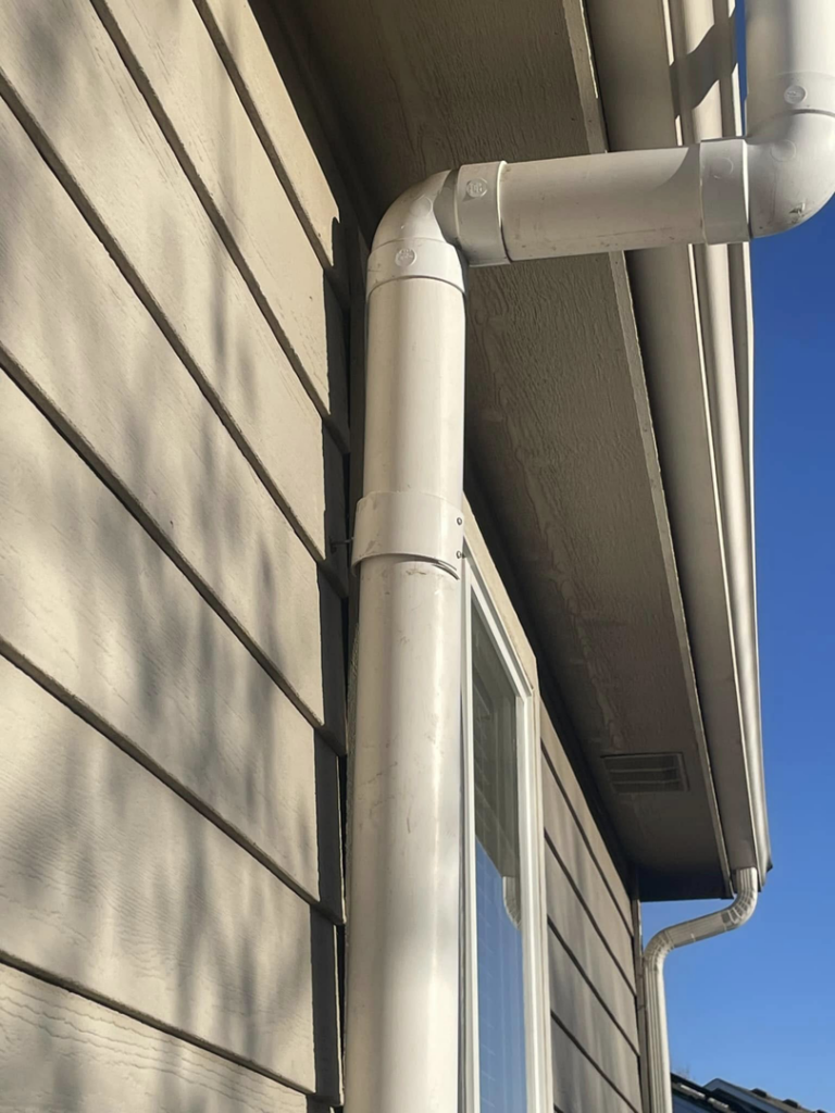 An exterior white PVC pipe for a radon mitigation system installed on a house by Rocky Mountain Radon Solutions in Fort Collins, CO.