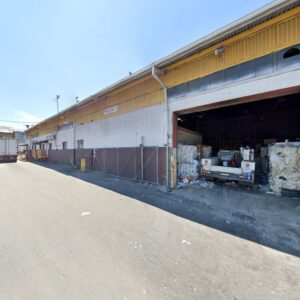 Exterior view of the All American Recycling Corp. facility in Jersey City, NJ, showing baled recyclable materials and a truck near the open bay.
