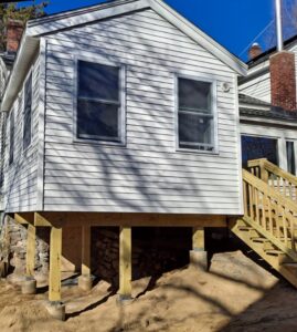House exterior with new siding and a wooden deck and stairs, a remodel project by Modern Remodel Build & Design in Worcester, MA.