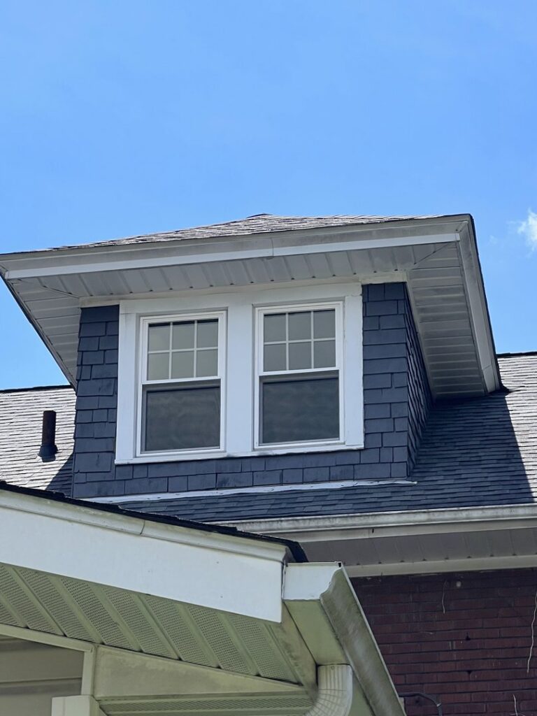 The exterior of a house featuring newly installed blue siding on a dormer, a renovation project by OG Renovations in Huntington, WV.