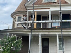 A worker on scaffolding performing exterior siding and trim repair on a house by Usa Construction of Danbury LLC in Danbury, CT.