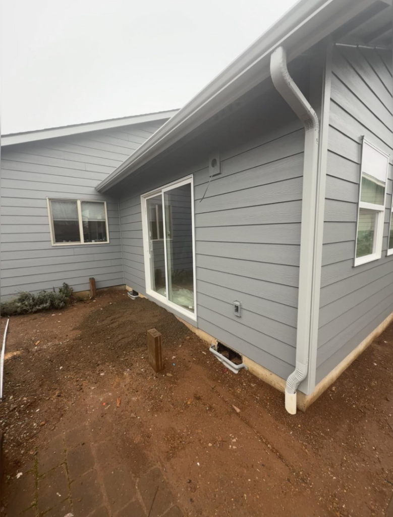 Exterior view of a new sliding door, gray siding, and gutters by Reborn Construction LLC in Wilsonville, OR.
