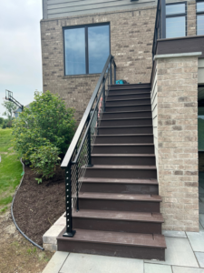 Exterior stairs with modern cable railings leading up to a brick house, installed by Nader Builders in Ann Arbor, MI.