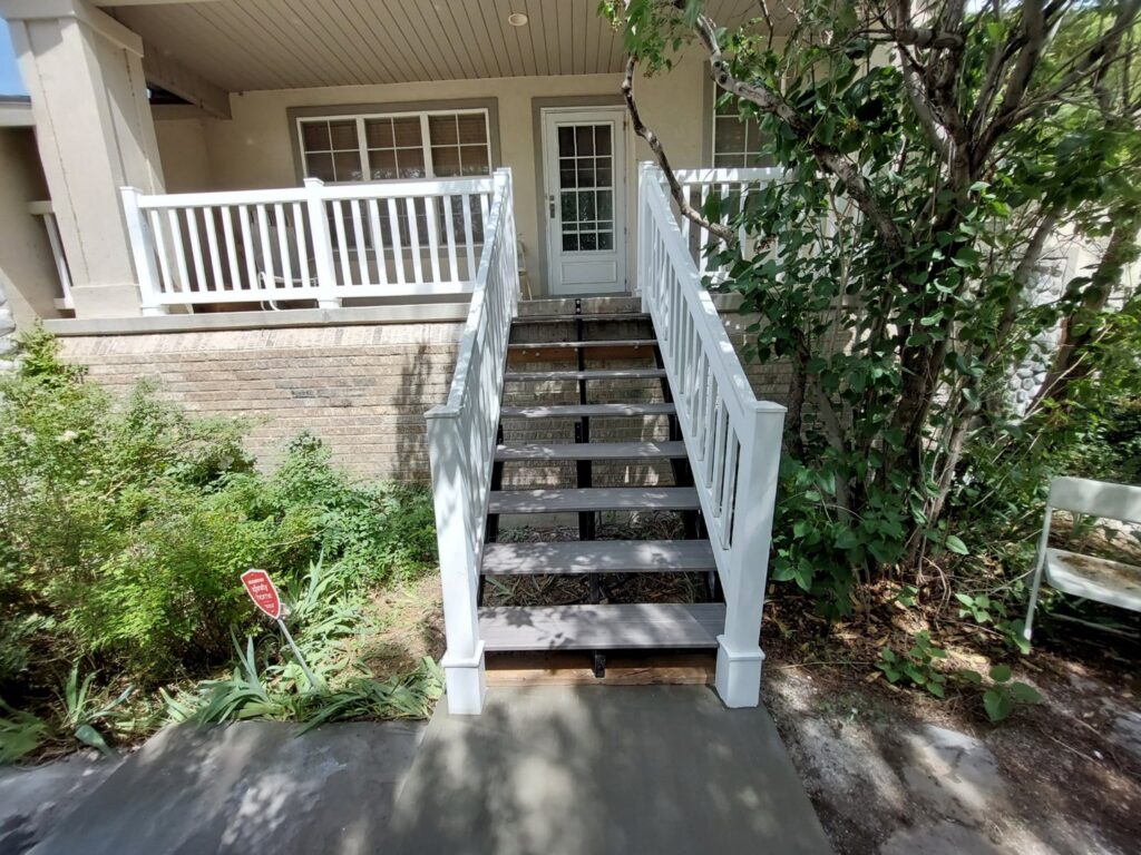 Newly installed exterior stairs and white railings leading to a house, a service provided by Jake and Jake Construction LLC in Sandy, UT.