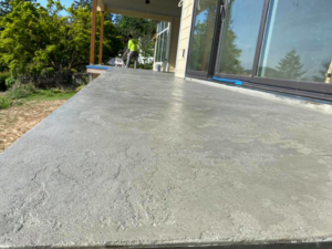 A handyman applying a durable exterior surface coating with a worker in the background for Titan Exteriors in Hillsboro, OR.