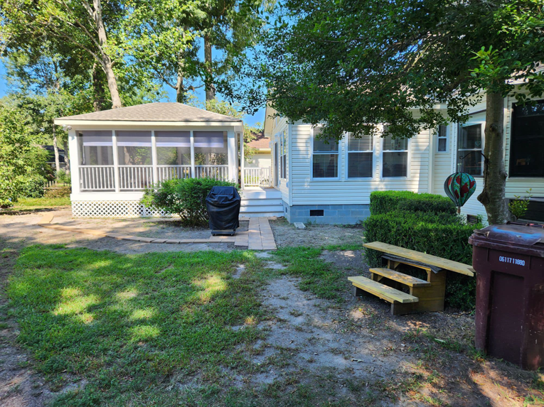 An exterior view of a house showcasing a completed screened-in porch addition by WHE Construction in Virginia Beach, VA