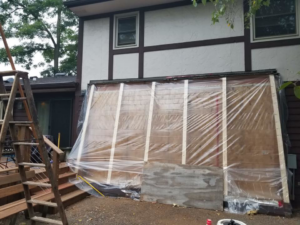Exterior wall framing covered with protective plastic sheeting during a construction project by Gerlach Handyman in Eau Claire, WI.
