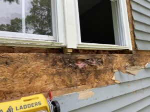 Exterior wall repair showing damaged siding and exposed insulation under a window, handled by Granite State Handyman & Home Repair in Derry, NH.