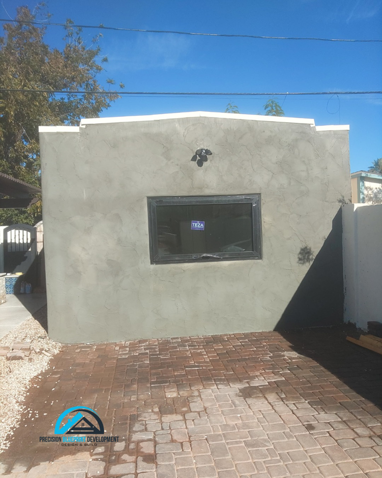 An exterior wall with new stucco finish and a recently installed window by Precision Blueprint Design & Development in San Tan Valley, AZ.