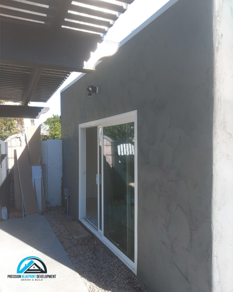 An exterior wall with new stucco finish and a recently installed sliding glass door from Precision Blueprint Design & Development in San Tan Valley, AZ.