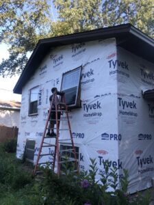 A handyman from Nordic Construction installing an exterior window on a house in Plymouth, MN.