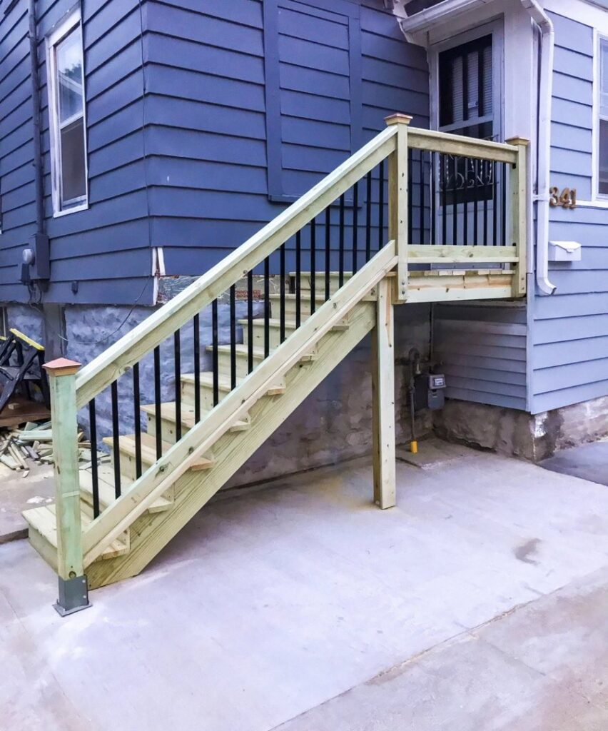 Newly constructed exterior wooden stairs with black metal railings by L12 Construction LLC in Oshkosh, WI.