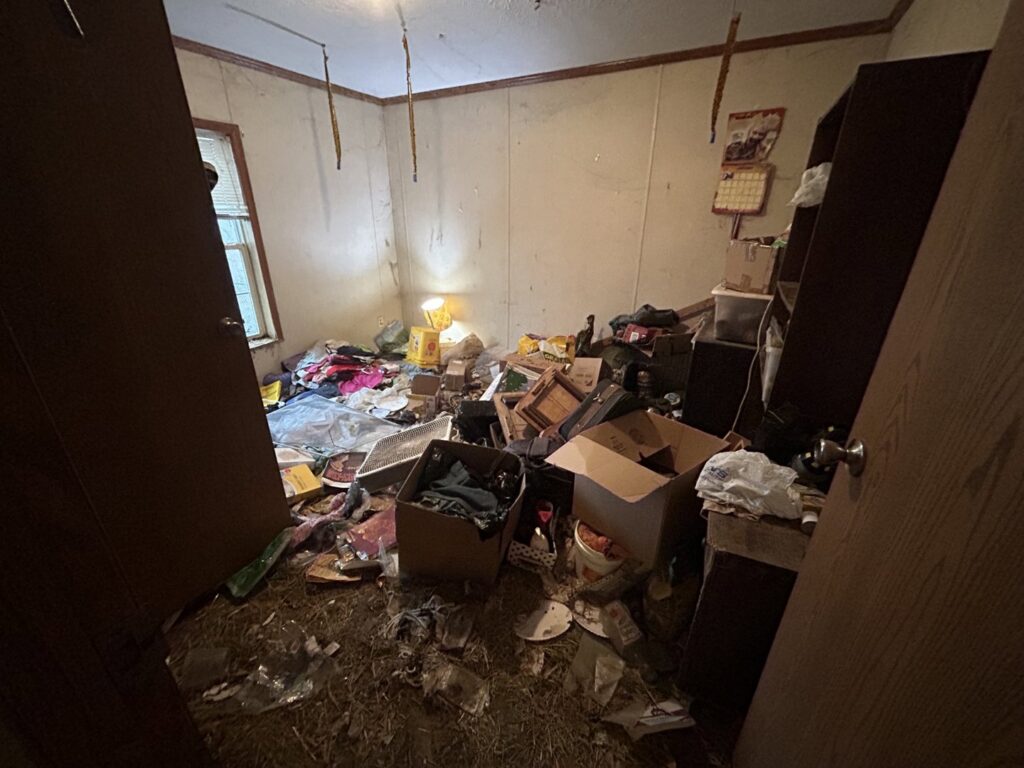 An extremely cluttered room, likely a hoarder cleanout, before junk removal by Rosales Junk Removal in Des Moines, IA.