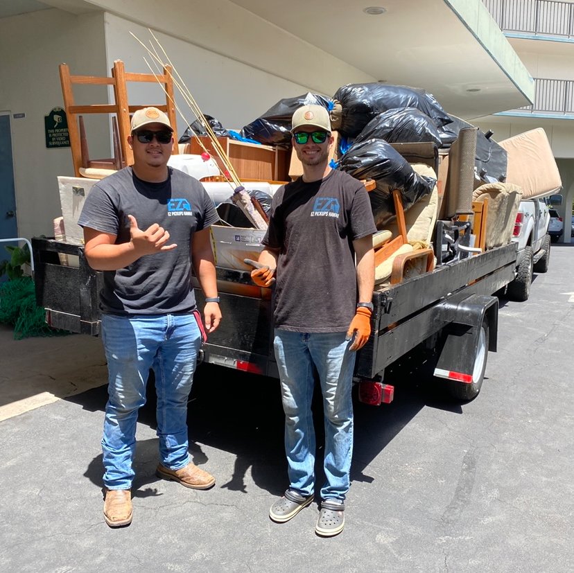 Two EZ Pickups Hawaii LLC team members standing proudly in front of a trailer loaded with furniture and junk after a successful removal job in Hilo, HI.