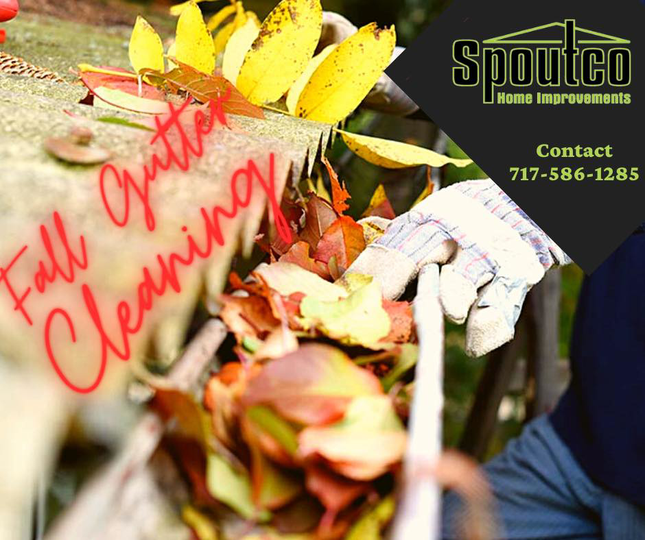 A person wearing gloves cleaning fall leaves from a gutter, a service by Spoutco Home Improvements in York, PA.