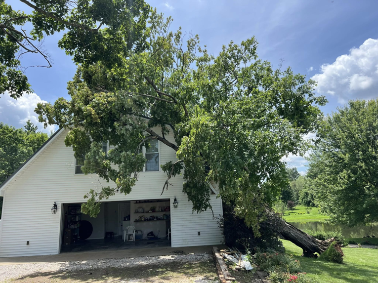 A large tree fallen onto a house, showing storm damage, requiring tree service from Hardin County Tree Service LLC Kentucky in Elizabethtown, KY.