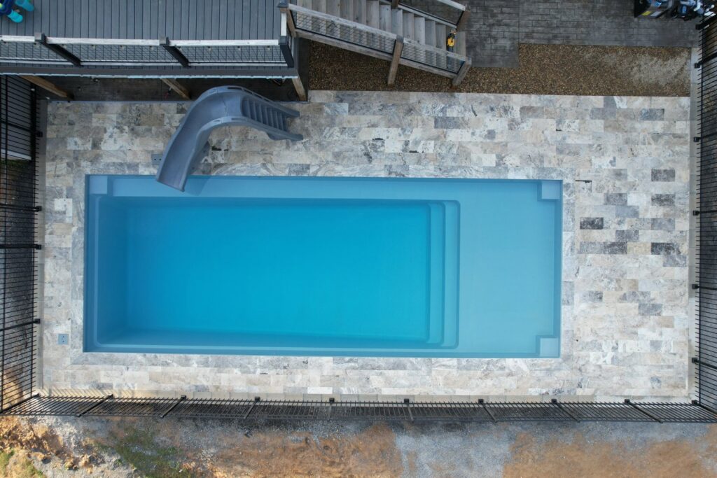 A family-friendly pool featuring a slide and spacious patio area, installed by Southern Pool Solutions in Knoxville, TN.