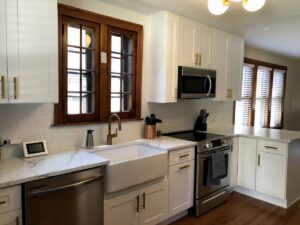 A beautifully remodeled kitchen with white cabinets, gold hardware, and a farmhouse sink by Inland Home Remodeling Inc. in Chicago, IL.