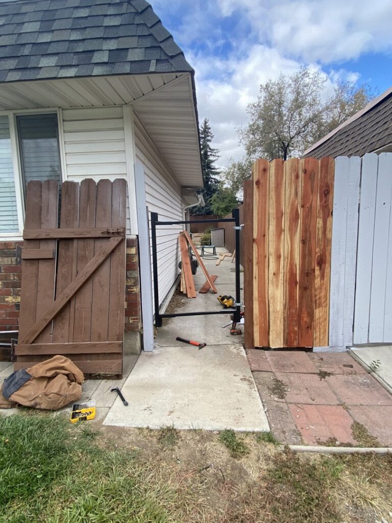 An outdoor fence gate under construction or repair, with tools on the ground, by The Handy Nevadan LLC in Reno, NV.