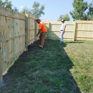 Two handymen installing a new wooden fence in a backyard for PRO HANDY FIXER in Kearney, NE.