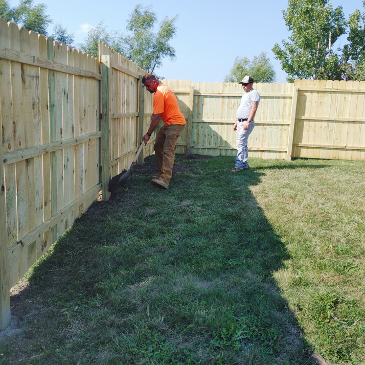 Two handymen installing a new wooden fence in a backyard for PRO HANDY FIXER in Kearney, NE.