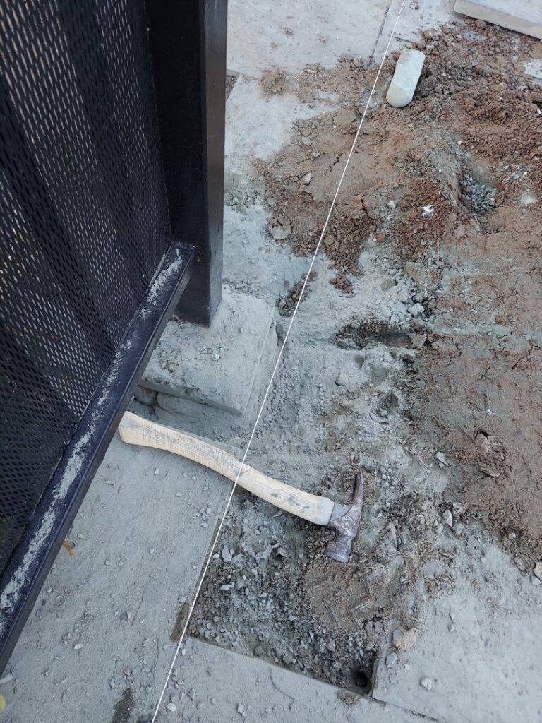 A metal fence post installation in progress with a hammer and string line, provided by Handyman Services of Albuquerque in Albuquerque, NM.