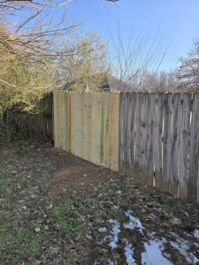 A wooden fence with new panels installed, showing fence repair work by Creekside Handyman NWA in Centerton, AR.