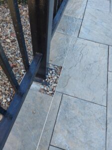 A metal fence post being installed on a paved patio with a string line, a service offered by Handyman Services of Albuquerque in Albuquerque, NM.