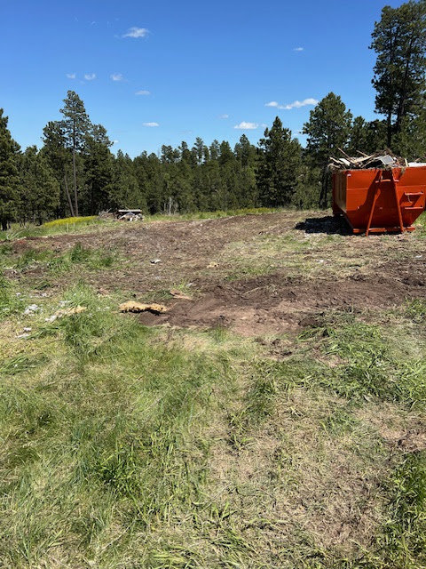 An orange Rushmore Dumpster filled with construction debris and junk on a cleared job site in Rapid City, SD.