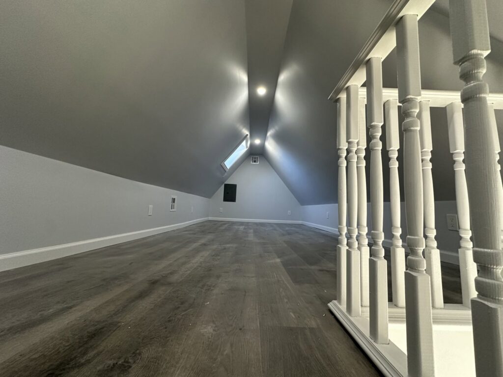 A newly finished attic space with new flooring and recessed lighting by Universal Builders LLC in New Haven, CT.