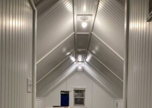 A finished attic space with white paneling and new lighting, completed by DCM Multi Service llc in Harrisburg, PA.