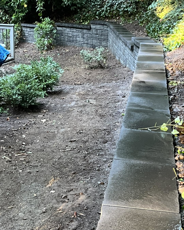 A finished backyard retaining wall with new landscaping, completed by MRLM Construction LLC in Beaverton, OR.