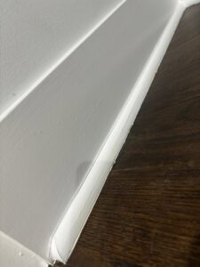 A close-up view of newly installed white baseboard trim and flooring, demonstrating attention to detail by Keeler Construction Group Inc. in Blue Island, IL.