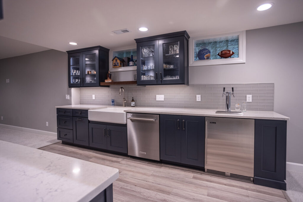 A finished basement bar featuring dark cabinets, subway tile backsplash, and a beer tap, completed by Legacy Builders Group in Cincinnati, OH.
