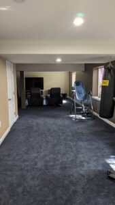 A finished basement area with new carpet and painted walls, suitable for exercise, by QCON LLC in Aurora, CO.