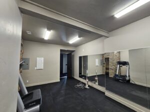A spacious, finished basement home gym with large mirrors and modern lighting by Jedi Bldrs in Colorado Springs, CO.