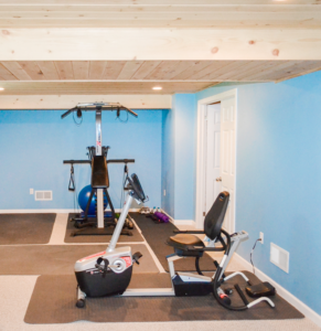 A finished basement transformed into a home gym with a wood plank ceiling by Patriot Construction in Rochester, NY.