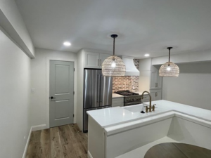 A newly finished basement kitchenette with white cabinets and brick backsplash by Smith Construction Services in Cincinnati, OH