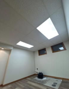 A newly finished basement room with bright ceiling lights and a clean floor by I Need a Guy Handyman Services LLC in Moorhead, MN