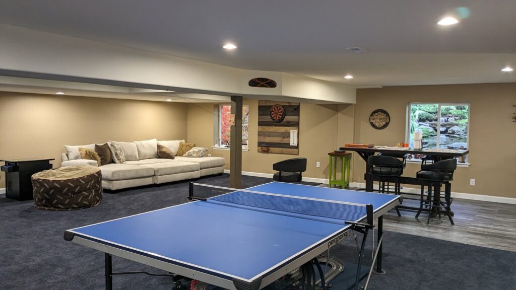 A finished basement featuring a comfortable living space and game area by QCON LLC in Aurora, CO.