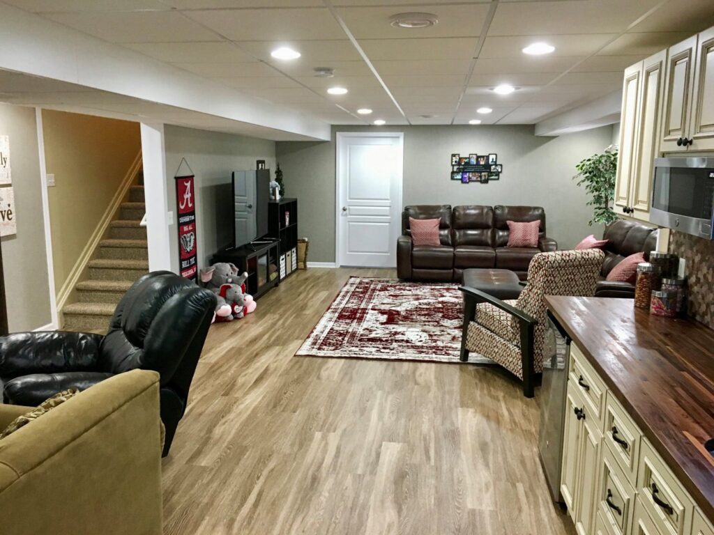 A wide view of a fully finished basement with a comfortable living area and a custom bar by Impressive Basements in Westland, MI.