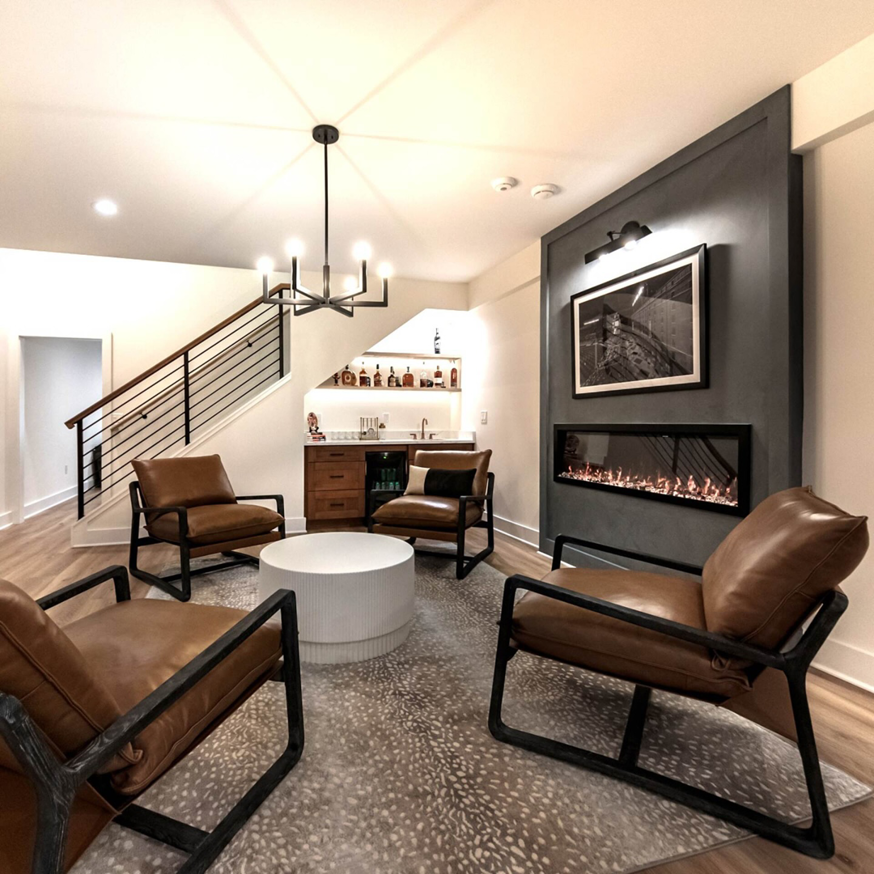 Finished basement living area with a modern fireplace and wet bar by BasementRemodeling.com in Rockville, MD.
