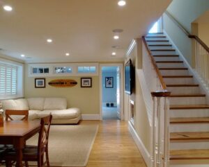 A finished basement living area with a comfortable couch, dining table, and recessed lighting, completed by Paradise Found Construction in Cary, NC.